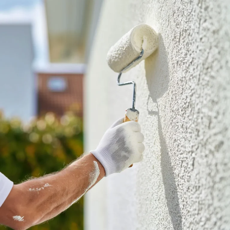 Close-up of a paint roller on a white stucco wall